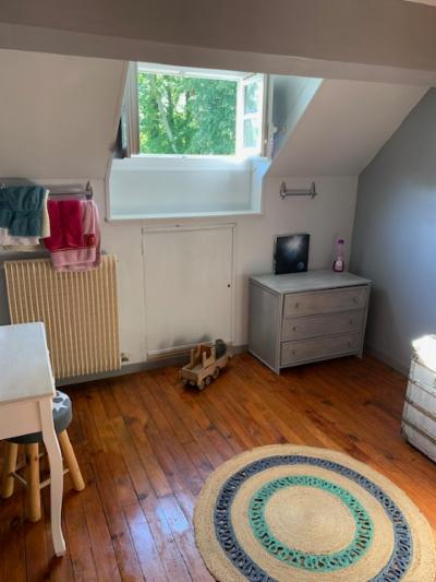 Chambre d'enfant sous combles : commode, jouet en bois, tapis rond et petite table