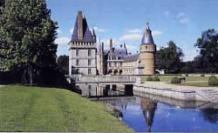 Château à tourelles au bord d'un canal, dans un parc arboré
